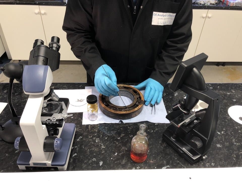 A failed bearing being inspected under the microscope by a lab analyst