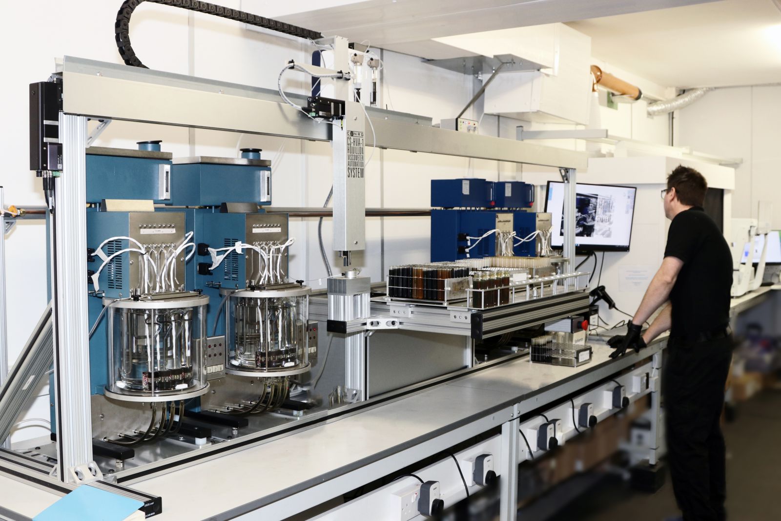 The automated viscometer robot processing racks of oil samples in the lab